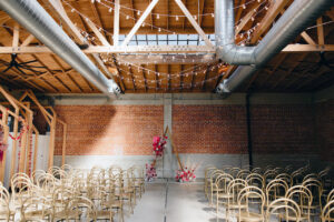 Rows of chairs layed out in a vintage warehouse, lit from above by a skylight.